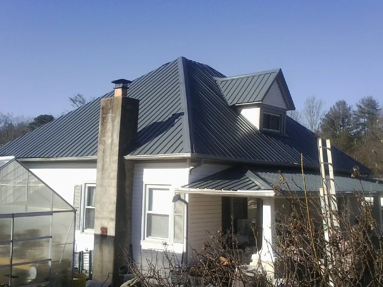 Dark blue standing seam metal roof on a white farmhouse with dormer — Slate & Tile Roof Repair by Roofing Brothers in Post Falls