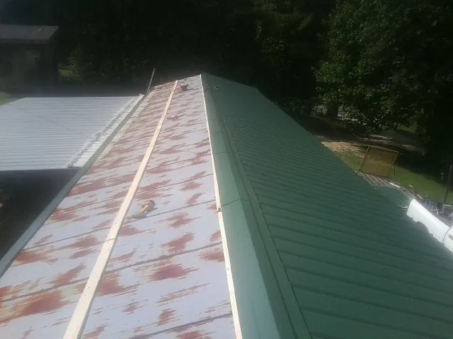 Old rusted panels beside newly installed green metal roofing — Wind Damage Roof Repair by Roofing Brothers in Post Falls