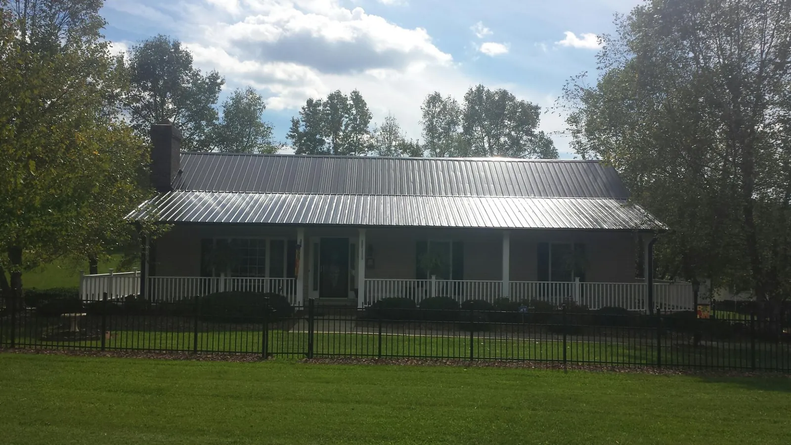 Gray metal roof on a brick ranch with a full width front porch — Gutter Guard Installation work by our crew in Post Falls