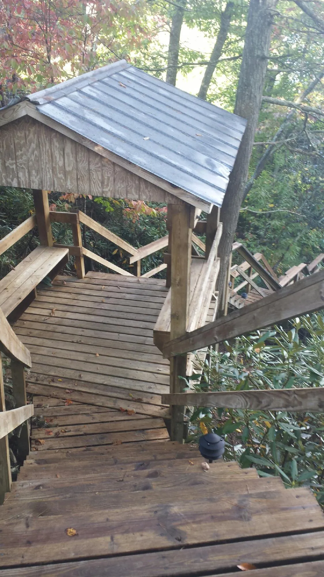 Metal roofed shelter over wooden steps on a wooded walkway — Skylight Repair & Installation work by our crew in Post Falls