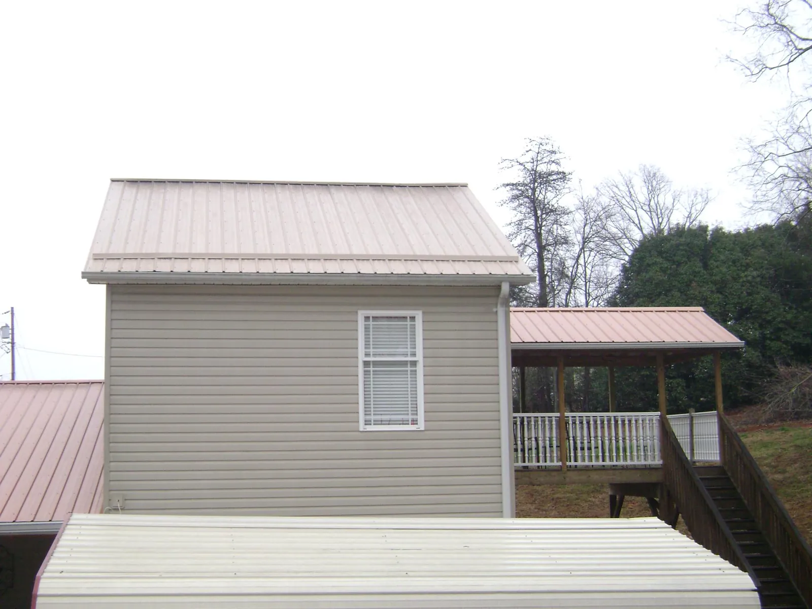 Tan metal roofs on a two story addition and attached porch, from a Roof Replacement job in Post Falls