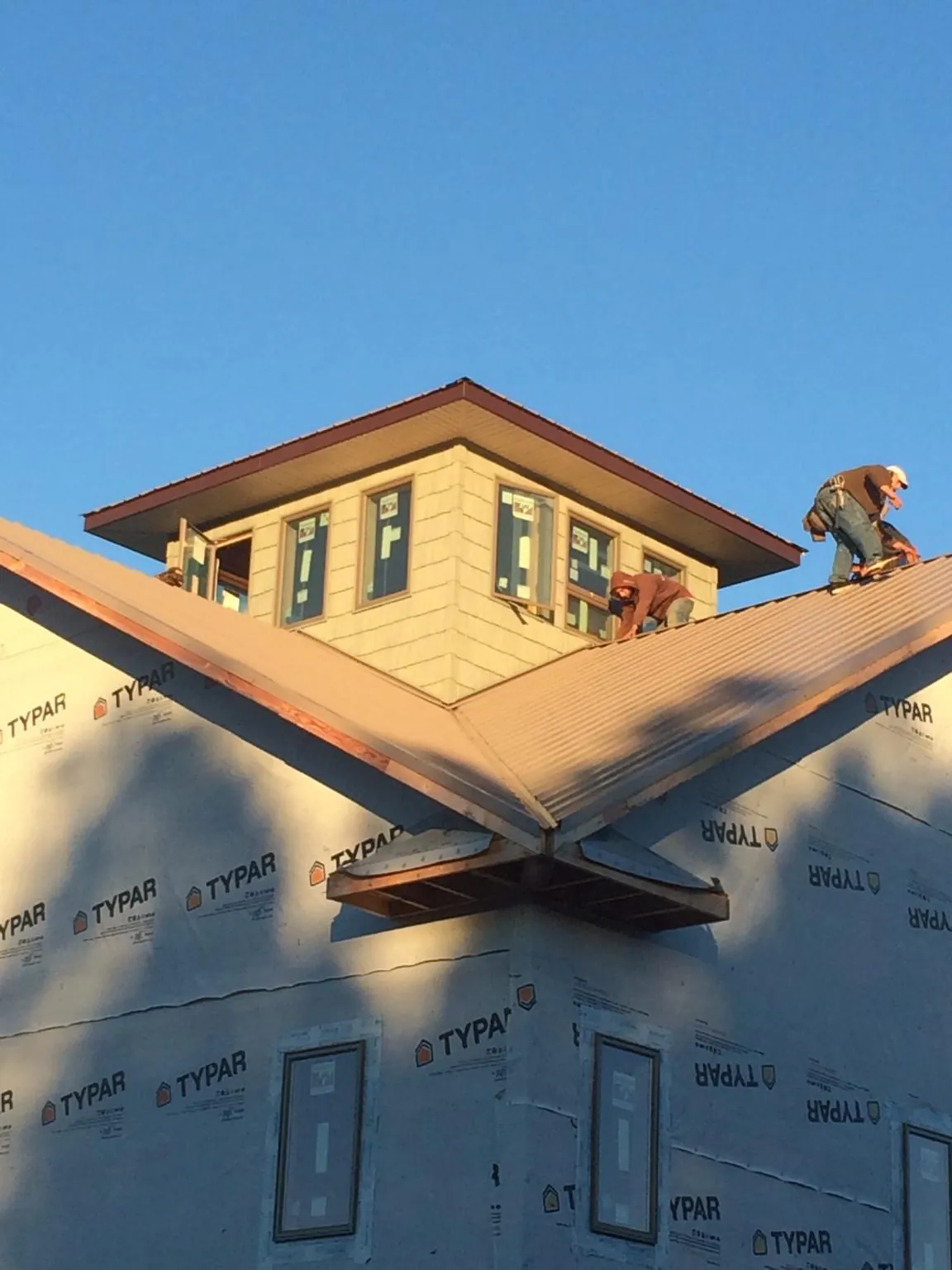 Roofers working around a rooftop cupola on a new metal roof at sunset — Roof Waterproofing in Post Falls by Roofing Brothers